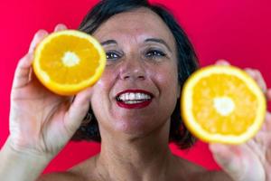 portrait of attractive middle aged woman is holding in her hands two half cut oranges photo