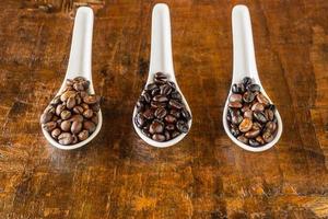 A collage of coffee beans in spoon showing various stages  through to roast photo