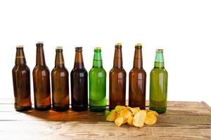 set glass bottles of beer mock up with no label and potato chips on wooden table isolated, copy space photo