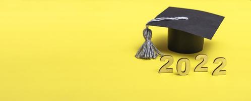 caja de regalo en forma de gorro de graduación. 2022 concepto de lanzamiento en el espacio de copia de fondo amarillo. bandera foto