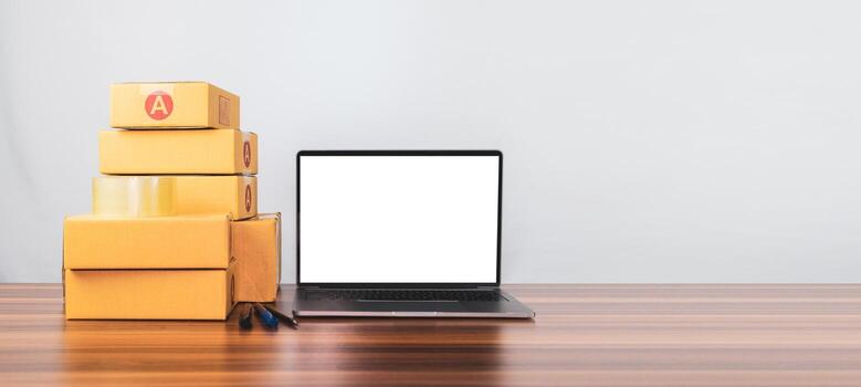 la caja para enviar a los clientes está sobre la mesa y hay una computadora para recibir pedidos de la tienda en línea, vendiendo negocios en línea que se están volviendo populares hoy en día, servicios de tienda en línea convenientes foto