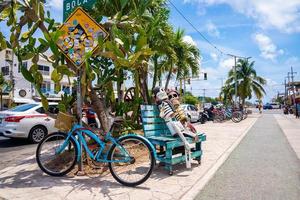 Skeletons carving on wooden bench with parked bicycle and signboard in city photo