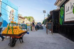 Mango fruit cart with pedestrians at roadside restaurant with signboards