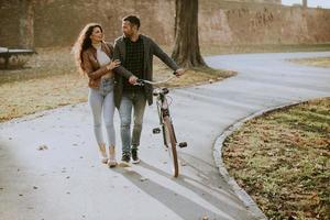 Young couple walking with bicycle in autumn park photo