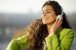 Bastante joven escuchando música con el teléfono inteligente por el río en un soleado día de otoño foto