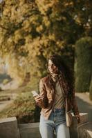 Mujer joven con teléfono móvil en el parque en un día soleado de otoño foto