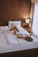 mujer feliz usando un teléfono móvil mientras está acostado en la cama foto