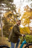 Young man with electric bicycle in the autumn park photo