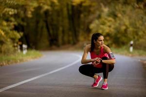 Mujer joven tiene un descanso durante el entrenamiento en el bosque de otoño foto