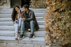 Young couple sitting on outdoor stairs on a autumn day and using mobile phone photo
