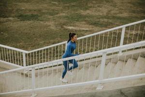 Mujer joven en traje azul corriendo en las escaleras al aire libre en la mañana de otoño