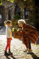 Grandmother having fun with her little granddaughter and holding basket full of flowers