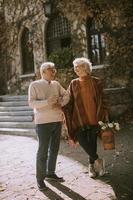 Senior couple walking with basket full of flowers in autumn park photo