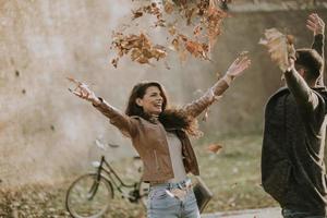 Young couple having fun with autumn leaves in the park photo