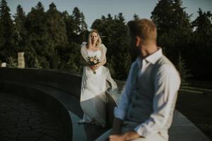 Young newlywed man sitting in front of his young bride photo