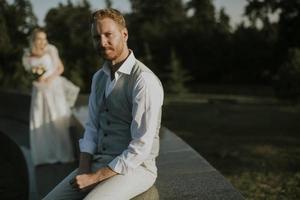 Young newlywed man sitting in front of his young bride photo