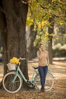 mujer joven, con, bicicleta, utilizar, smartphone, en, otoño, parque