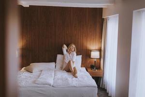 Young woman sitting on the bed at room photo