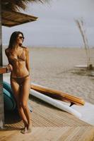 Mujer joven en bikini de pie junto al bar de la playa en un día de verano foto