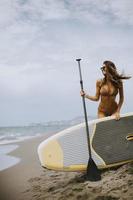 Young women with paddle board on the beach on a summer day photo