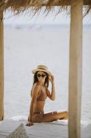 Young woman with hat and sunglasses relaxing in the beach lounge photo