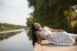 mujer joven relajante en el muelle de madera en el lago foto