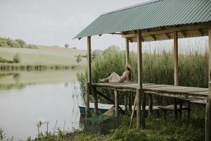 mujer joven relajante en el muelle de madera en el lago foto