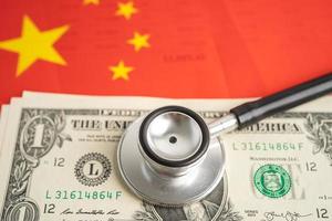 Black stethoscope on China flag background with US dollar banknotes, Business and finance concept. photo
