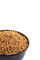 Fenugreek seeds in bowl isolated on white background photo