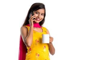 Bastante joven llamando a un dispositivo smartphone mientras bebe una sabrosa bebida de café o té foto