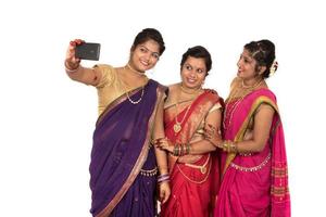 Las niñas tradicionales indias tomando selfie con smartphone sobre fondo blanco. foto