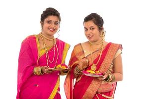 Portrait of Indian Traditional Girls holding diya and flower thali, Sisters celebrating Diwali or deepavali holding oil lamp during festival on white background photo
