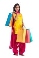 Beautiful Indian young girl holding and posing with shopping bags on a white background photo