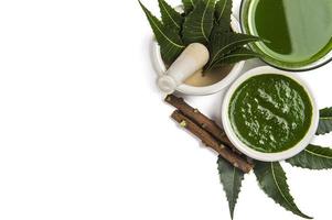 Medicinal Neem leaves in mortar and pestle with neem paste, juice and twigs on white background photo
