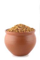 Fenugreek seeds in clay pot isolated on white background photo