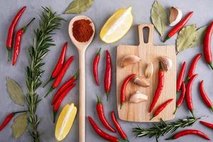 Pods of red hot pepper among other spices on gray surface photo