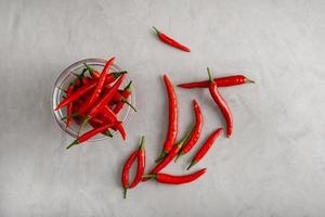 vainas de pimiento rojo picante en un tazón de vidrio sobre yeso gris. foto