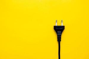 Black electric plug connector on yellow background. Top view. Copy, empty space for text photo