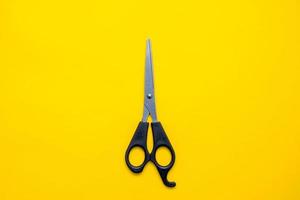 Black scissors on a yellow background. Top view. Copy, empty space for text photo