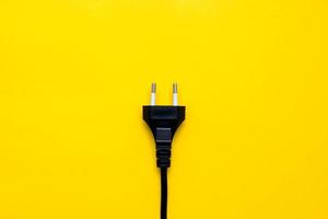 Conector de enchufe eléctrico negro sobre fondo amarillo. vista superior. copiar, espacio vacío para texto foto