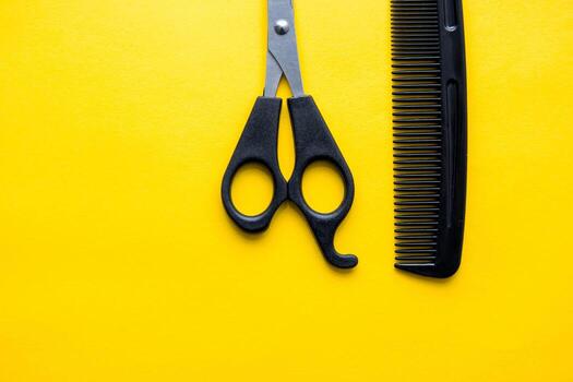 Scissors and comb for hairdresser on a yellow background. Top view. Copy, empty space for text photo