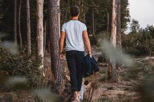 guapo posando al aire libre en el bosque se encuentra descalzo sobre un tronco, vistiendo chaqueta a cuadros. lugar para texto o publicidad foto