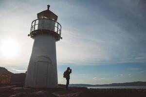 Silhouette of man taking photo on lighthouse background and dramatic sky. Place for text or advertising