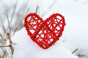 Wooden red heart on background of snow-covered tree branches. Eco-friendly valentines day. photo
