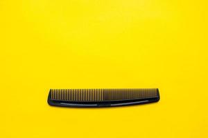 Black plastic hair comb on yellow background photo