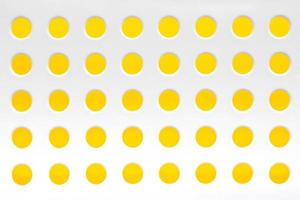 White plastic background with regular holes on yellow background. Copy, empty space for text photo