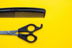 Scissors and comb for hairdresser on a yellow background photo