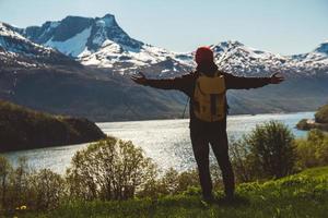 Young man with a backpack standing on the background of mountains and lake. Space for your text message or promotional content. Travel lifestyle concept photo