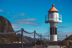 faro en el muelle en el fondo de las montañas y el cielo azul en las islas lofoten. lugar para texto o publicidad foto