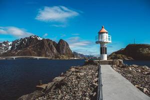 faro en el muelle en el fondo de las montañas y el cielo azul en las islas lofoten. lugar para texto o publicidad foto